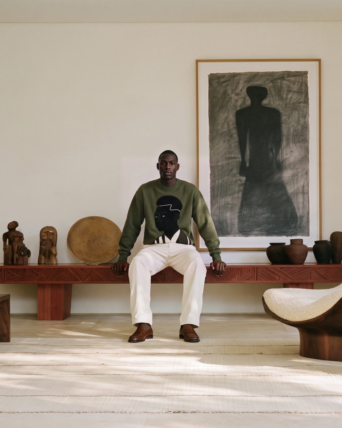 Model seated on a carved wooden bench wearing the Songa knit sweater